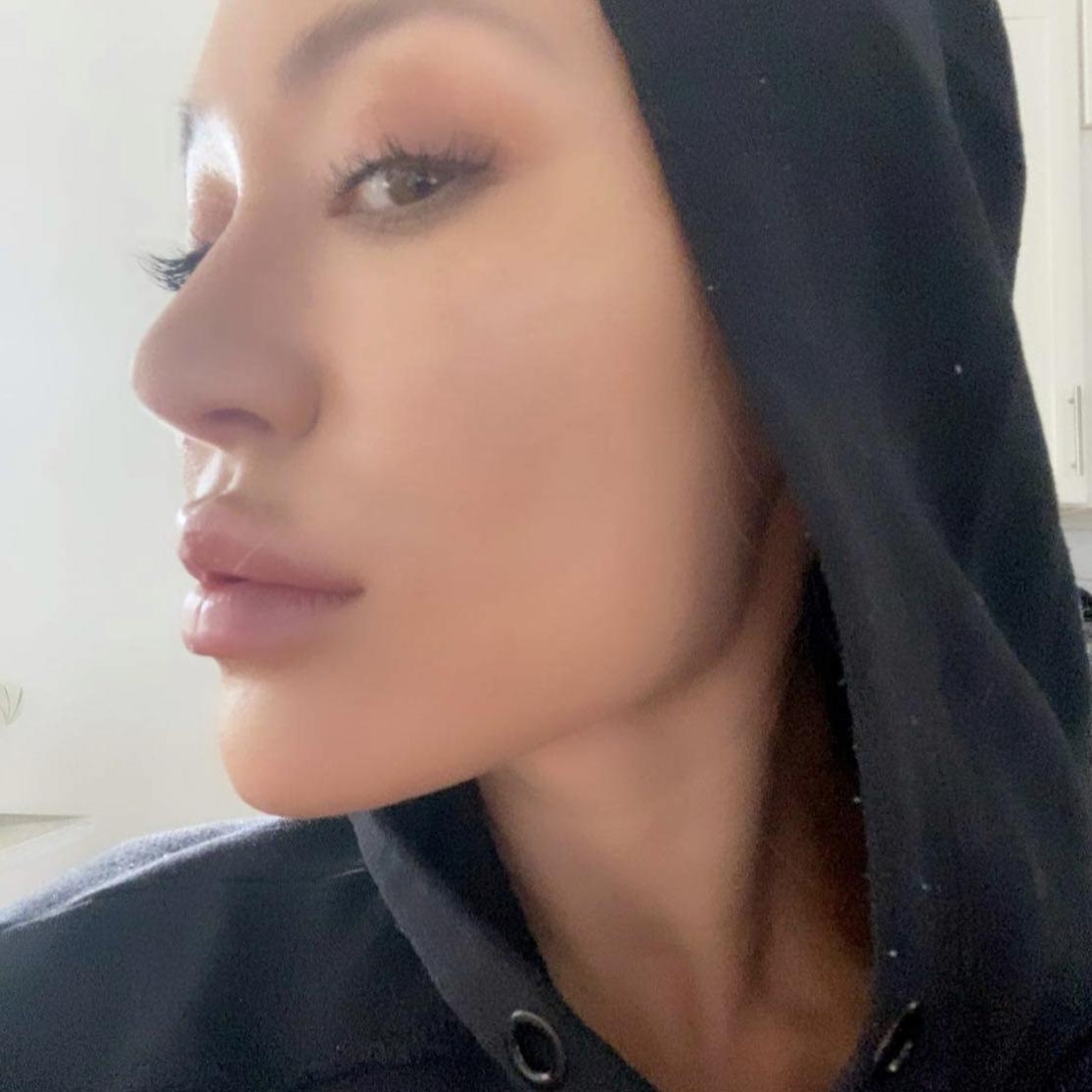 a woman in a black hoodie, flaunting her puckered lips